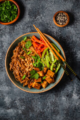 Soba noodles with vegetables and fried tofu in a bowl.