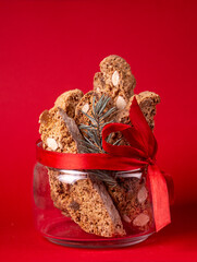 Traditional italian Christmas New Year dry cookies biscuits biscotti cantuccini in glass bowl on red background. Biscotti di Prato.