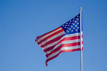 American flag blowing in the wind, blue sky