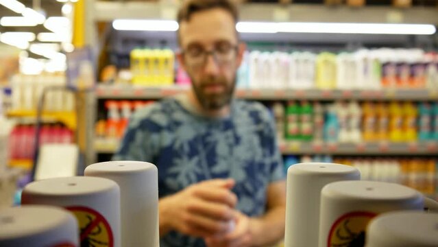 Close-up of many anti mite sprays in a store and a male buyer chooses one