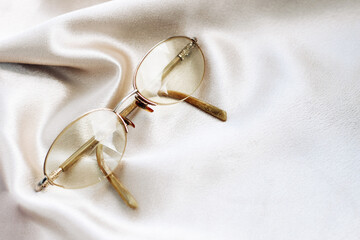 Glasses in a gold frame with diopters on a silk background