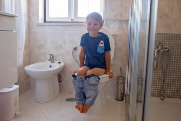 Cute child, boy, sitting on the toilet