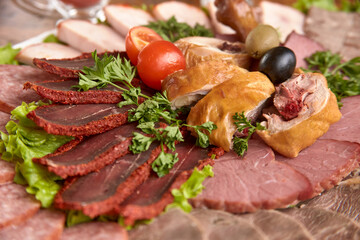 Part of plate with cold cuts with choice - salami, pieces of sliced ham, sausage, chicken, qazi horse meat, tomatoes on salad, close-up, shallow depth of field