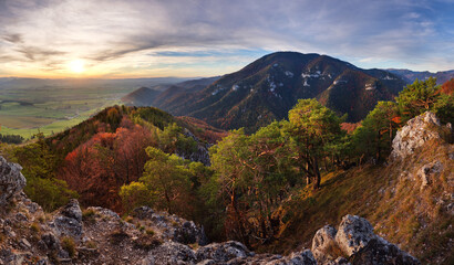 Panorama landscape at sunset with autumn forest, rocks, sun and mountain.