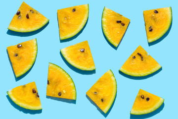 fresh sliced yellow watermelon like background, flat lay with hard shadow on blue background, creative decoration of summer concept