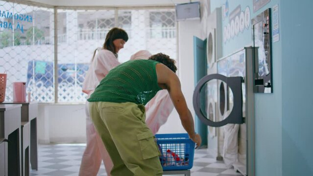 Teen friends having fun in laundromat room. Cute couple doing laundry together