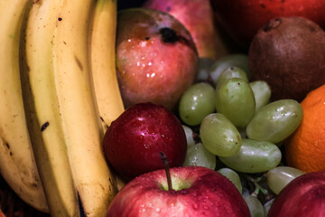 Assorted colorful fruits in basket. Apple, banana, grapes, pineapple, oranges etc. Food photography. Macro. Close-up.