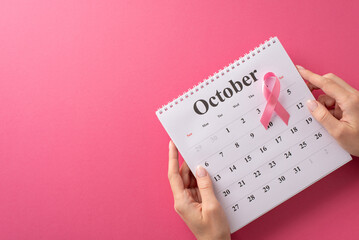 Advocating Breast Cancer Awareness Month. Bird's-eye view of woman's hands cradling a calendar and a pink ribbon on pink isolated space, with copyspace for text or promotions