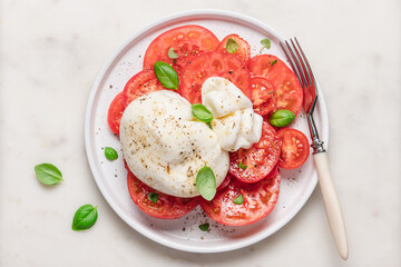 Gourmet tomato salad with burrata cheese, olive oil and spices. Italian food concept. Food background top view with copy space