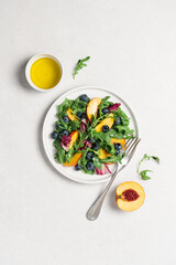 Peach arugula blueberry salad in plate on white background. Delicious fruit salad