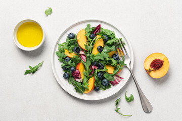 Peach arugula blueberry salad in plate on white background. Delicious fruit salad