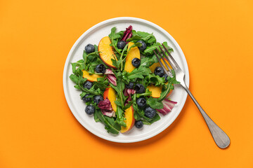 Peach arugula blueberry salad in plate on orange background. Delicious fruit salad