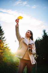 A woman holding a yellow leaf in her hand