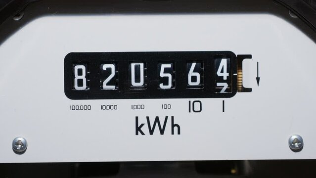 A close-up of a domestic electric meter and measuring dial numbers. Slow zoom-in out of focus to in focus. Concept, meter readings, power, energy, high bills, inflation and meter reading. kWh sign.