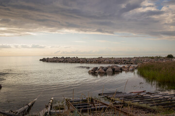 Sunset view from parispea beach in Lahemaa national park, Estonia. Image shows sunset with partial clouds and a calm sea washing over the rocky water break and beach. August 2023