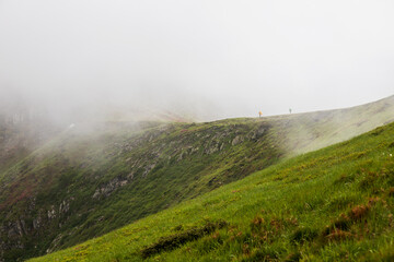 Two tourists climb a mountain in the fog