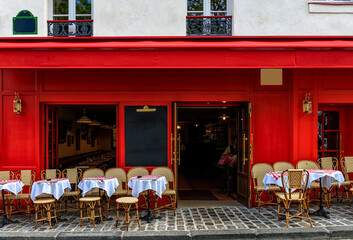 Fototapeta premium Cozy street with tables of cafe in quarter Montmartre in Paris, France. Architecture and landmark of Paris. Paris cityscape.