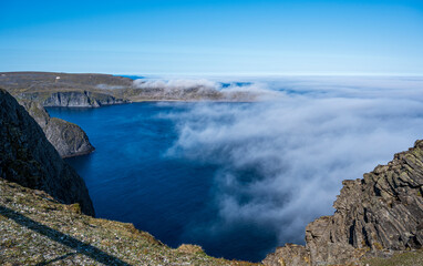 Obraz premium Beautiful view from the North Cape of the rocky cliffs and blue water of partly cloudy Barents Sea