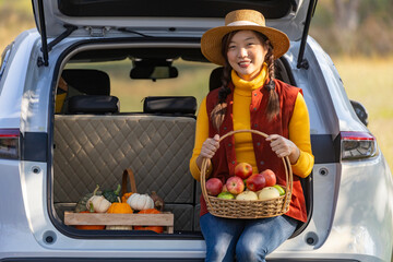 Happy Asian farmer girl carrying produce harvest with homegrown organics apple, squash and pumpkin...