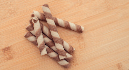 Delicious chocolate wafer roll sticks on the wooden table. closeup. flatlay