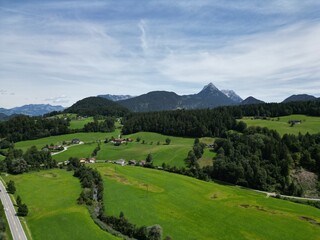 Fototapeta na wymiar This drone photo shows bright green pastures between trees in the picturesque hills of the Austrian Alps 