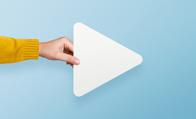 Hand holding white media player button icon on yellow background