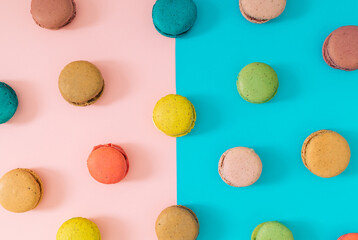 Creative colorful pattern made of various macarons on pastel pink and blue background. Minimal sweet food concept. Trendy macaron cookies pattern background. Yummy flat lay idea.