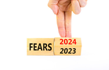2024 fears new year symbol. Businessman turns a wooden cube and changes words Fears 2023 to Fears 2024. Beautiful white background, copy space. Business 2024 fears new year concept.
