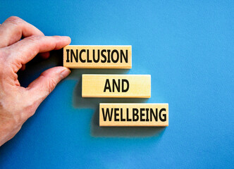 Inclusion and wellbeing symbol. Concept words Inclusion and wellbeing on wooden block. Beautiful blue table blue background. Doctor hand. Motivational inclusion and wellbeing concept. Copy space.