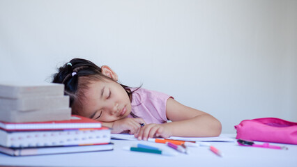 Portrait Of Cute Little Asian Female Child Sleeping At Desk Tired After Doing School Homework,...