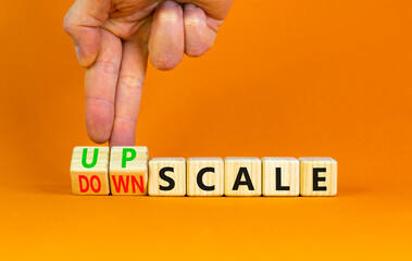 Upscale or downscale symbol. Concept words Upscale or Downscale on wooden cubes. Beautiful orange table orange background. Businessman hand. Business upscale or downscale concept. Copy space.
