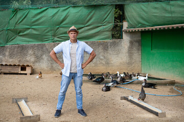 The man - the owner of the farm is happy against the backdrop of the poultry yard.