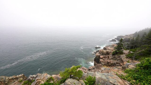 wide view of foggy rocky coastline with waves crashing ashore