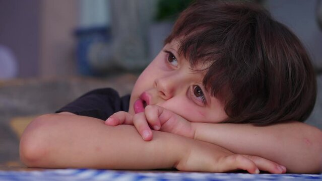 Restless small boy leaning on restaurant table waiting for food to arrive, struggles with boredom. close-up face