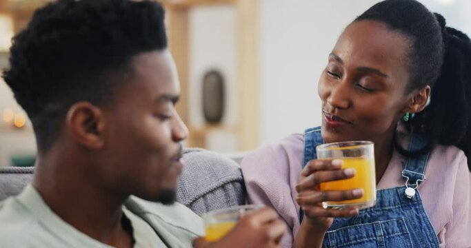 Happy, black couple and orange juice in home living room on sofa in healthy diet, nutrition or wellness. African man, woman and drink fruit in glass, organic vitamin c and funny vegan laugh together