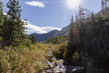 vue sur une vallée entre des montagnes lors d'une journée ensoleillée avec un ruisseau qui coule...