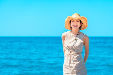海で麦わら帽子を被る笑顔の日本人女性