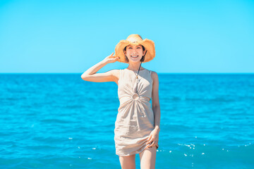 海で麦わら帽子を被る笑顔の日本人女性