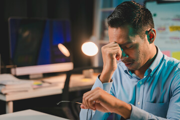 Male employee working late and stressed with failed work Young asian businessman working hard on...