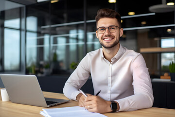 close up portrait of happy handsome successful businessman sitting at office table and hand holding pen cheerful filling business documents or signing contract agreement.