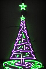 Fototapeta na wymiar Dark christmas tree illuminated with neon lights on dark background, wallpaper christmas banner Ai Generative