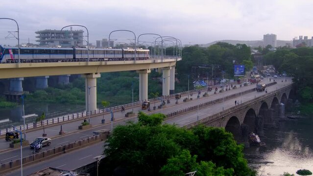 Metro runs on an overhead track, Vehicle moves along the Pune metro rail road near Sangam Bridge, now the Indian urban mass transit metro railway system. Pune, Maharashtra, India.