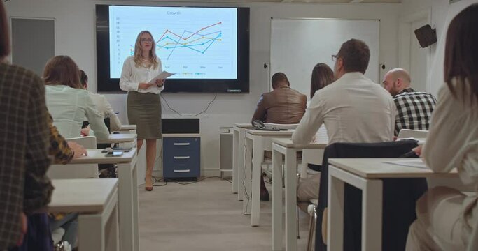 Senior female trainer giving lectures to diverse office coworkers prior the test, trucking motion