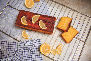 lemon cupcake with two pieces cut off on a beige table with a checkered towel and scattered lemons