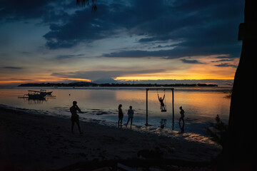 A colorful sunset at Gili Air beach in Indonesia. Calm sea, blue evening sky, red-orange sky and silhouettes of people