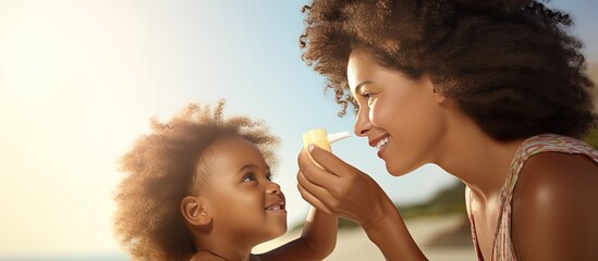 Mother applying sunscreen on daughter s nose at beach Black woman applying sun lotion on girl s face African american girl with sunblock cream