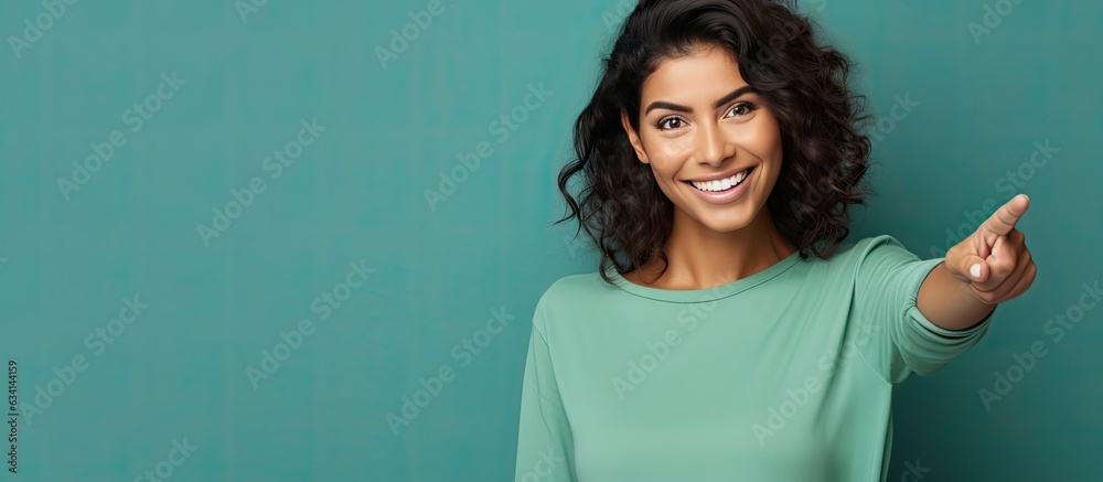 Aufkleber Smiling cheerful Hispanic woman happily pointing to side and upwards displaying object in empty area