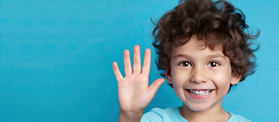 Portrait of a five year old boy displaying five fingers on a blue background with empty space