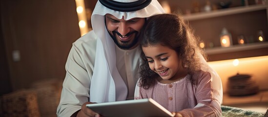 Young Arab father and his adorable daughter enjoying time together at home using a tablet for online shopping