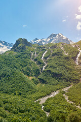 Naklejka premium view of the glacier with a waterfall and a blooming meadow